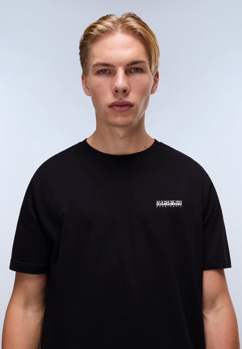 Maglietta nera a maniche corte in cotone. Presenta un piccolo logo bianco sul lato sinistro del petto. Design semplice e dritto con scollatura tonda.