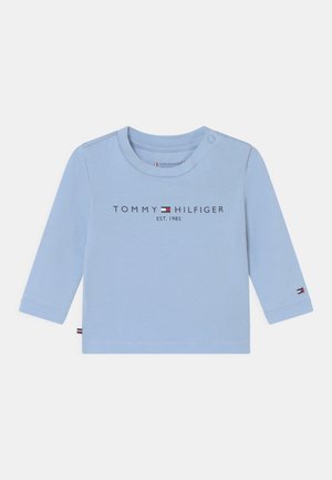 Lyseblå langærmet babytrøje med Tommy Hilfiger-logo og lille flagemblem på ærmet, trykknap ved halsudskæringen.