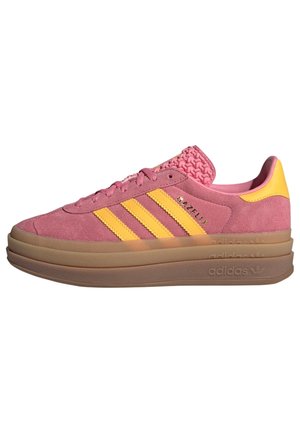 Roze suède Adidas Gazelle sneaker met gele strepen, grove bruine zool en gestructureerde tong, zijaanzicht.