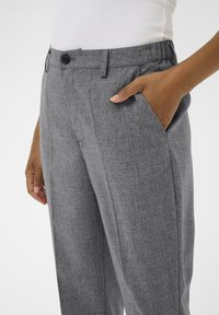 Pantalons texturés gris à coupe décontractée, avec une fermeture par bouton et des poches latérales. Le tissu semble léger et respirant.