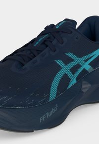 Σκούρο μπλε αθλητικό παπούτσι ASICS με τυρκουάζ λογότυπο, μαύρα κορδόνια και επενδεδυμένη σόλα με την ένδειξη "FF Turbo²", εμφανιζόμενο από γωνία εμπρός-πλευράς.
