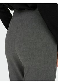 Grå skräddarsydda byxor i en texturerad tygkvalitet, med en elegant design och hög midja. Passformen är nära kroppen med synliga sömmar.