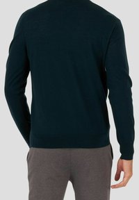 Donkerblauwe trui van lichtgewicht breiwerk, met een ronde hals en geribde manchetten, gecombineerd met grijze broek voor een casual look.