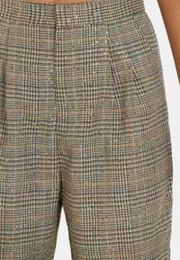 Pantalons à taille haute en tartan avec un tissu texturé présentant des accents de fil multicolores et de subtils sequins brillants.