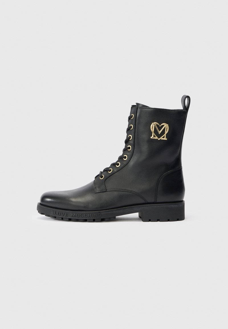 Botim de tornozelo em couro preto com ilhós dourados e logótipo, design com atacadores, sola texturizada e "EU AMO MOSCHINO" estampado no calcanhar.