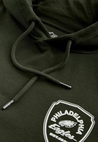 Sweat à capuche vert foncé avec cordons et un logo blanc des Philadelphia Eagles représentant une tête d'aigle et du texte sur le devant.