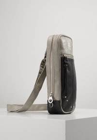 Szaro-czarna skórzana torba na ramię, z zamkiem błyskawicznym, regulowanym paskiem i metalowymi akcentami. Gładkie i teksturowane powierzchnie.