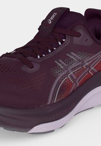 Dunkelroter Asics-Laufschuh mit Schnürsenkeln, gemusterten Seitenstreifen und gedämpfter Sohle mit FF Blast Max-Technologie.