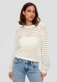 Weißer, offener Strickpullover mit geripptem Kragen und Bündchen. Kombiniert mit hellblauen Jeans. Die Textur ist luftig mit horizontalen Mustern.