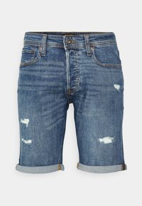Shorts de mezclilla en un lavado azul medio, con un aspecto desgastado, dobladillos deshilachados, puños enrollados y un diseño clásico de cinco bolsillos.