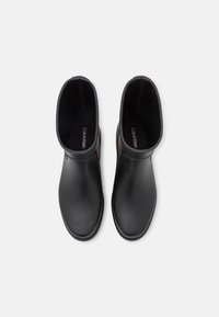 Botas de tobillo de goma negra con un acabado suave y punta redondeada. Presentan paneles laterales elásticos y plantilla interior con el nombre de la marca.