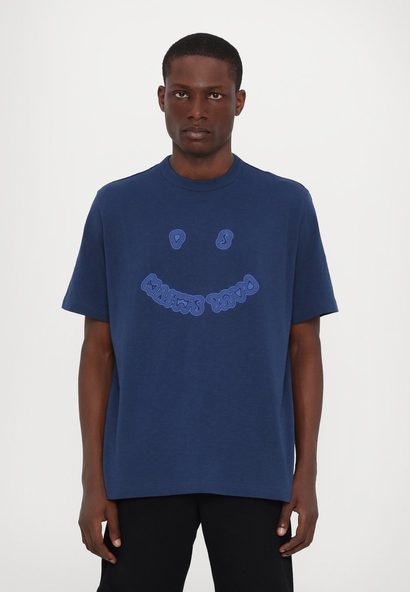 T-shirt en coton bleu marine avec un col rond. Présente un design graphique d'un smiley en bleu clair sur le devant. Coupe décontractée.