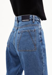 Ljusblå denimjeans med hög midja, med en mörk, märkesplåt på baksidan, stora bakfickor och en något blekt textur.