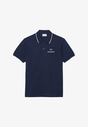 Marineblauwe katoenen polo met witte afwerking op de kraag en mouwen. Bevat een klein groen krokodillogo en een zak op de borst.