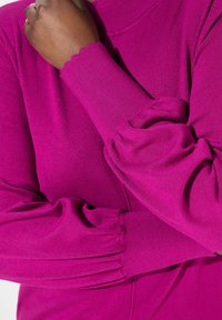 Enganliegendes Rollkragenpullover in lebhaftem Fuchsia. Verfügt über lange, gepuffte Ärmel mit gewellten Bündchen und einer glatten Strickstruktur.