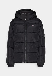 Veste matelassée noire avec capuche, comportant des sections horizontales matelassées, une fermeture éclair frontale et un petit logo sur la poitrine. Texture lisse.