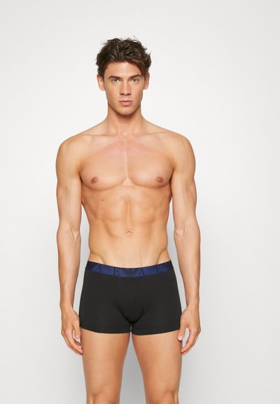Boxer briefs negros con una cinturilla elástica azul marino que presenta un patrón de logo repetido. Textura suave con un diseño ajustado.