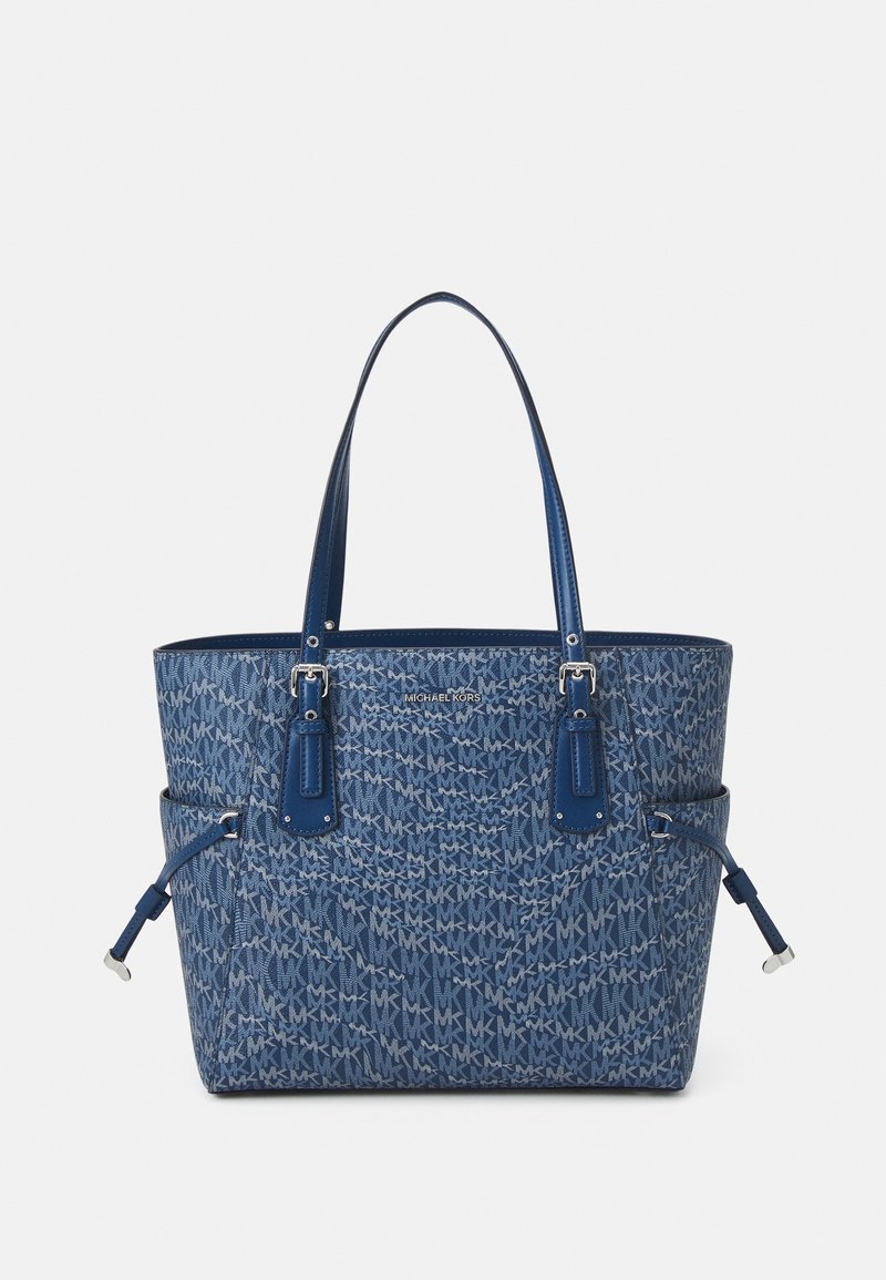 Sac fourre-tout bleu avec motif monogramme MK. Fabriqué en matériau texturé, il dispose de deux poignées supérieures, d'accents argentés et de détails à cordon sur les côtés.