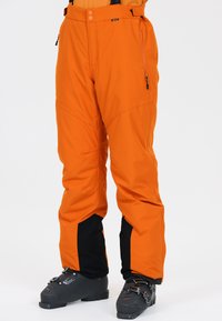 Pantalons de ski imperméables orange avec une coupe ajustée, accents noirs aux poignets et poches zippées pour une fonctionnalité accrue.