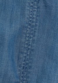 Blå denimtyg med en jämn textur och synlig sömnadsdetalj längs sömmen, som visar en jämn färg över hela ytan.