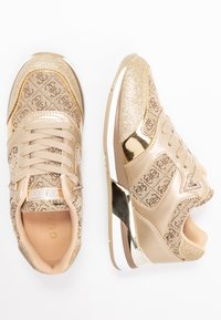 Kultaiset lenkkarit, joissa on kimalteleva design, metalliset yksityiskohdat, sileä nahka ja kuvioitu tekstiili päällinen nauhakiinnityksellä.