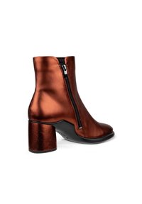 Kovově bronzové kotníkové boty s masivním podpatkem, vybavené bočním zipem a hladkým povrchem. Elegantní design s kulatou špičkou a kontrastní podrážkou.