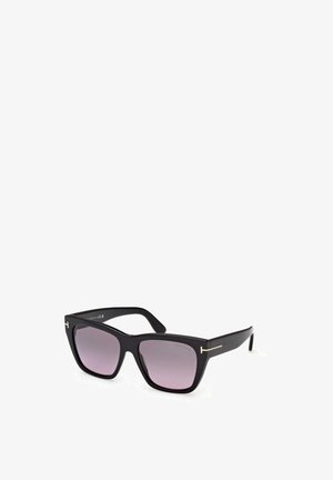 Occhiali da sole quadrati oversize neri con lenti sfumate scure e sottili dettagli dorati a forma di T sulle aste contro uno sfondo bianco.