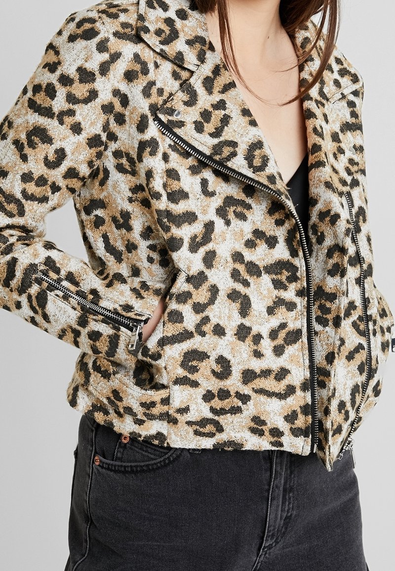 Kurtka w panterkę z teksturowanej tkaniny z metalowym zamkiem błyskawicznym, krótki krój i boczne kieszenie. Czarna para dżinsów dopełnia stylizację.