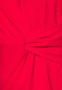 Ljust rosa klädfabric, med en snodd framsida och texturerad yta. Slätt, stretchigt material med en rynkad design.