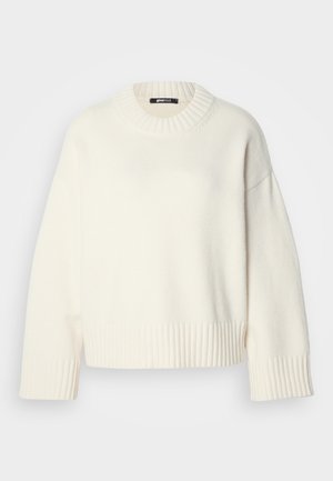 Kreemika värvi kampsun soonikkoes ümar kaelusega ja soonikuga servaga. Omadusteks on langetatud õlad ja lõdvestunud istuvus, valmistatud pehmest kangast.