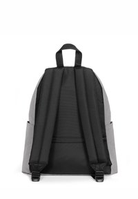 Mochila gris y negra con correas acolchadas y un asa de agarre. Cuenta con un bolsillo con cremallera y bolsillos laterales para almacenamiento adicional.