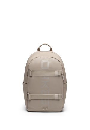 Bézs hátizsák két vízszintesen állítható pánttal, egy felső fogantyúval, oldalzsebekkel és diszkrét, függőleges márkajelzéssel az első panelen.