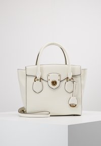 Biała skórzana torebka o strukturalnym designie, z zaokrąglonymi uchwytami, złotymi okuciami, zapięciem na zatrzask i odpinanym paskiem. Posiada akcentujące szwy.