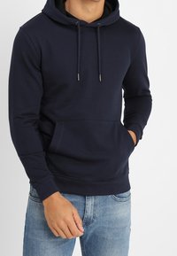 Sudadera con capucha azul marino hecha de tela suave, con bolsillo tipo canguro, cordón ajustable y puños acanalados para un mejor ajuste.
