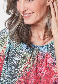 Mehrfarbige Bluse aus leichtem Stoff mit einem lebhaften abstrakten Muster in Rot-, Blau-, Grün- und Schwarztönen; runder Ausschnitt und lockere Passform.