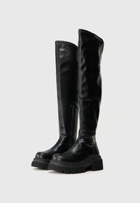 Čierne kožené čižmy po kolená s hladkým povrchom, masívnou čiernou podrážkou, bočným zipsom a jemným logom značky na vrchu.