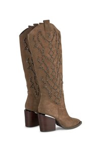 Botas de ante marrón hasta la rodilla con punta afilada, que cuentan con un patrón decorativo de cuentas y un tacón de madera apilada.