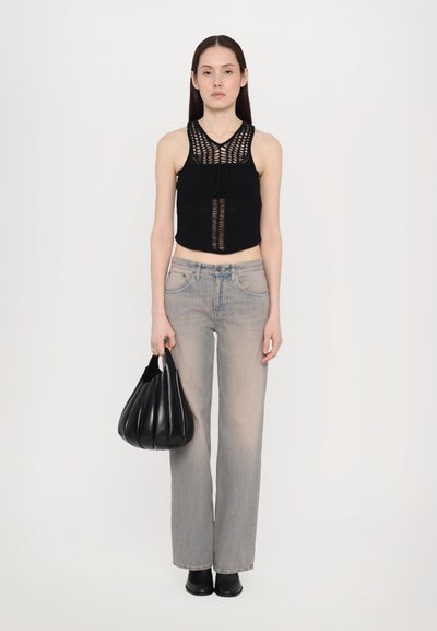 Top crop preto de malha com um padrão texturizado, jeans reto cinza claro e uma bolsa pregueada preta. Botas ankle pretas simples.