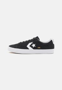Fekete velúr sneaker fehér kiegészítőkkel, csillag logóval, fűzős előlappal, kerek orral és bordázott gumitalppal.