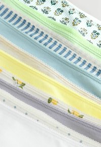 Pile de morceaux de tissu avec des motifs floraux, rayés, à pois et unis dans des tons pastel de bleu, vert, jaune, gris et blanc.
