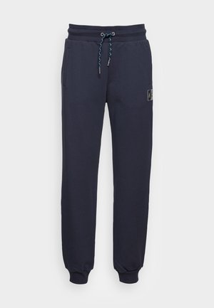 Pantalons de survêtement navy avec une taille élastique, des accents de cordon de serrage et des poches latérales ; poignets froncés ; comprend un patch logo sur la jambe.
