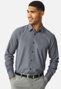 Cămașă cu mânecă lungă și nasturi, de culoare bleumarin, cu un model geometric. Prezintă un guler clasic, nasturi negri și o textură netedă.