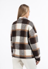 Uldternet jakke i grå, brun og creme med krave, oversized pasform og tekstureret finish. Synlige syninger og manchetter.
