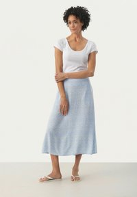 Gonna midi azzurro chiaro con un sottile motivo astratto, realizzata in un tessuto morbido. Abbinata a una t-shirt bianca aderente e sandali piatti.