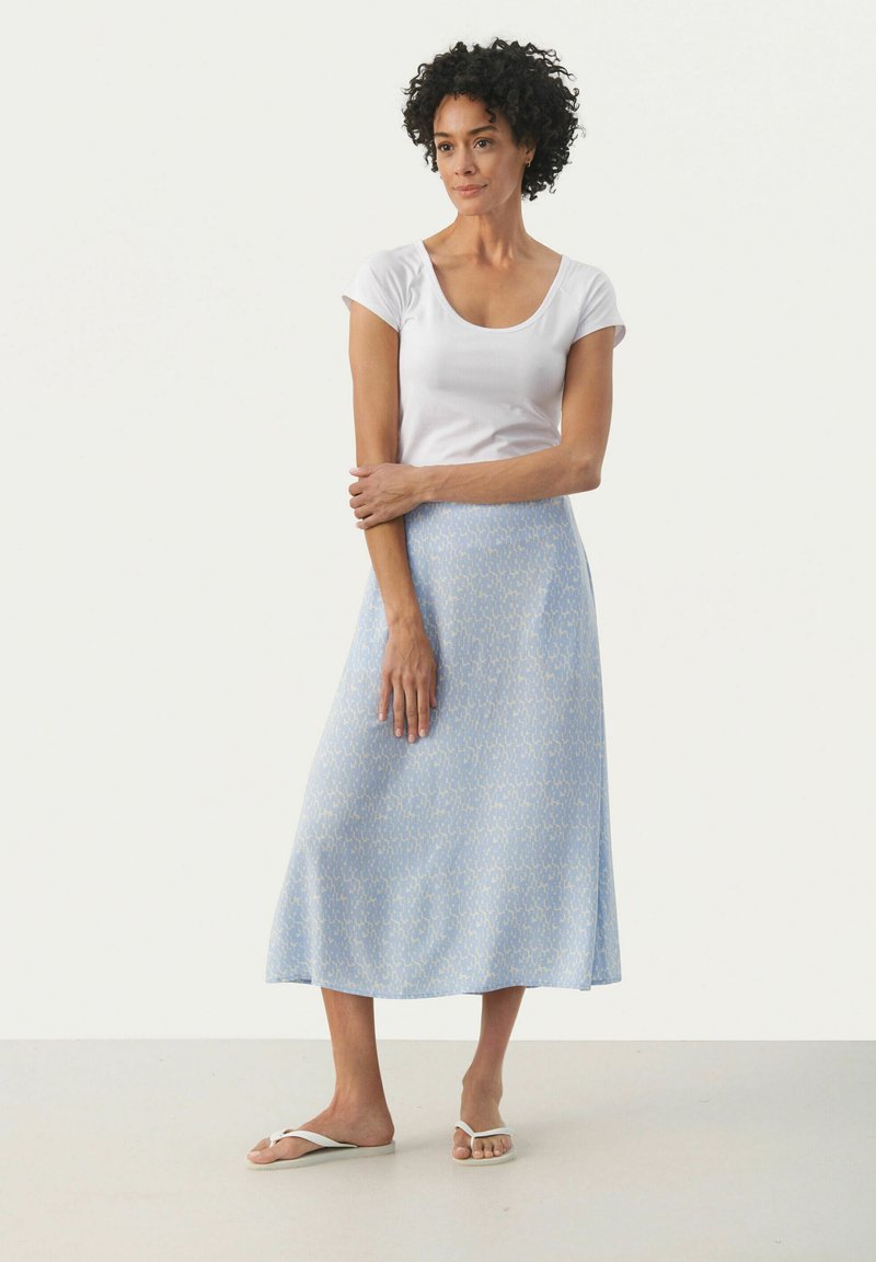 Gonna midi azzurro chiaro con un sottile motivo astratto, realizzata in un tessuto morbido. Abbinata a una t-shirt bianca aderente e sandali piatti.