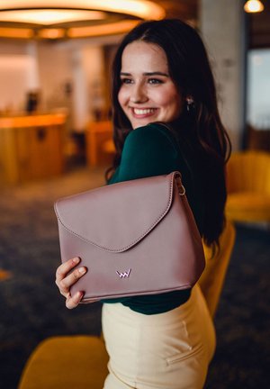 Soft pink synthetic leather handbag with a fold-over flap, featuring a small logo on the front and a smooth texture.