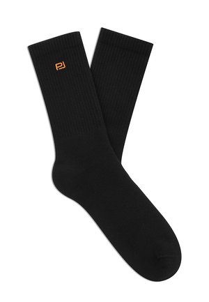 Czarne skarpetki do kostki z prążkowaną teksturą i małym pomarańczowym logo blisko góry na białym tle.