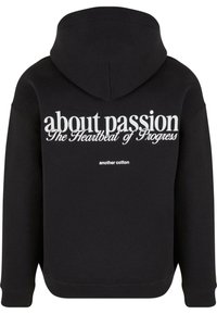 Felpa nera con cappuccio realizzata in cotone; presenta del testo bianco sul retro: "riguardo alla passione Il battito del progresso un altro cotone."