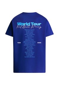 Μπλε μπλούζα με το κείμενο «World Tour Red Bull Racing» και μια λίστα με παγκόσμιες πόλεις που φιλοξενούν γεγονότα το 2026 στην πλάτη.