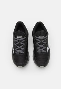 Scarpe sportive nere con un esterno in mesh testurizzato, lacci grigi e suole in gomma. Presentano un logo e un dettaglio laterale in bianco.